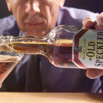 Man pouring a pint of Old Speckled Hen ale into a traditional beer glass.