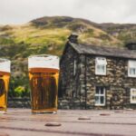 Lake District pubs with pints of beer outside a traditional stone inn in the mountains
