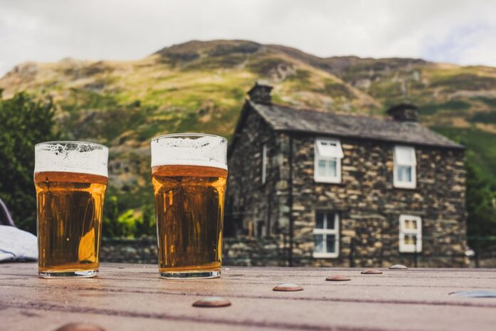 Lake District pubs with pints of beer outside a traditional stone inn in the mountains